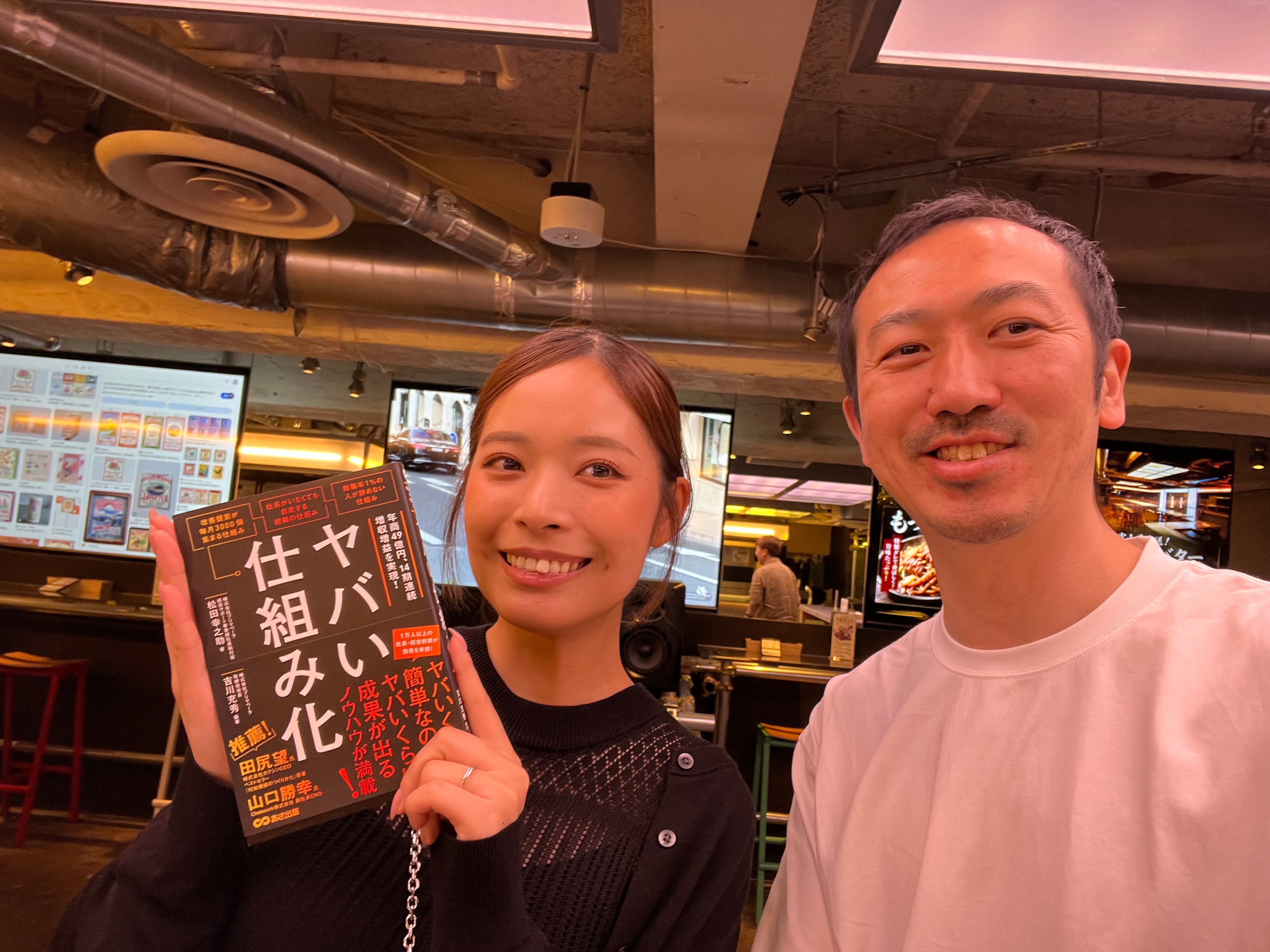 参謀BARで書籍を手に笑顔の2人